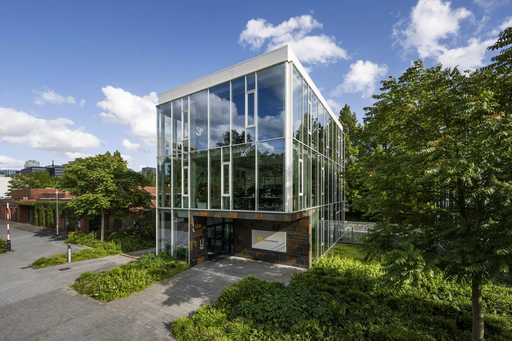 Modern glazen kantoorgebouw van Biometrisch aan de Fred. Roeskestraat, omgeven door groen en bomen.